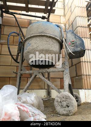 Elektrischer Betonmischer auf der Baustelle in der Nähe der Blockwand Stockfoto