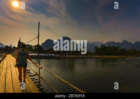 Backpacker geht über die Bambusbrücke über den Nam Song Fluss Vang Vieng Laos Stockfoto