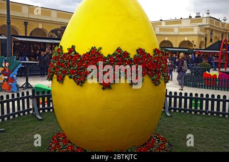 Im Freien jährlichen Ostermarkt in Wien, Österreich im Jahr 2016 beinhaltet ein großes gelbes Osterei mit roten Blumen kommen aus dem geknackten Ei. Stockfoto