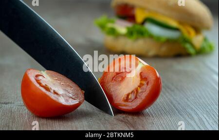 Schneiden Sie die Tomate mit einem scharfen Messer. Machen Sandwiches zum Frühstück. Stockfoto
