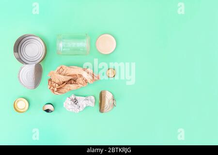 Recycelbarer verschiedener Müll bestehend aus Papier, Glas, Metall, Kunststoff auf dem grünen Hintergrund. Abfalltrennungskonzept. Flatlay, Kopierplatz. Stockfoto