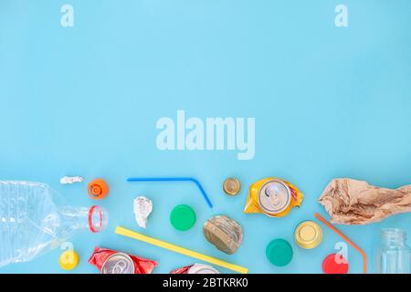 Recycelbarer verschiedenfarbiger Müll bestehend aus Papier, Glas, Metall, Kunststoff auf blauem Hintergrund. Abfalltrennungskonzept. Flatlay, Kopierplatz. Stockfoto