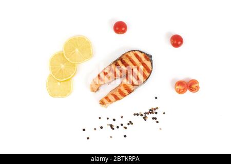 Gegrilltes Lachssteak mit Zitrone und Tomaten auf weißem Hintergrund isoliert. Stockfoto