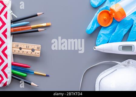 Schulbedarf mit medizinischer Maske, Digitalthermometer, chirurgischem Handschuh und Handdesinfektionsmittel. Flach lag Stillleben. Stockfoto