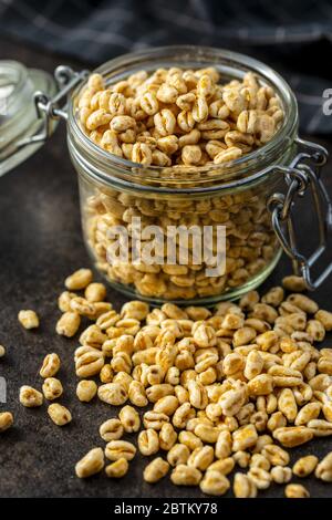 Gepuffter Weizen, der mit Honig bedeckt ist, im Glas. Frühstückszerealien. Stockfoto