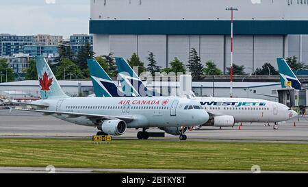 Richmond, British Columbia, Kanada. Mai 2020. Ein Airbus A320 von Air Canada (C-FTJQ) wird am 23. Mai 2020 zum Ankunftsflughafen von Vancouver International Airport gebracht. Im Hintergrund bleiben die WestJet Airlines-Jets aufgrund der verringerten Flugreisen wegen der COVID-19-Pandemie geparkt. Kredit: Bayne Stanley/ZUMA Wire/Alamy Live News Stockfoto