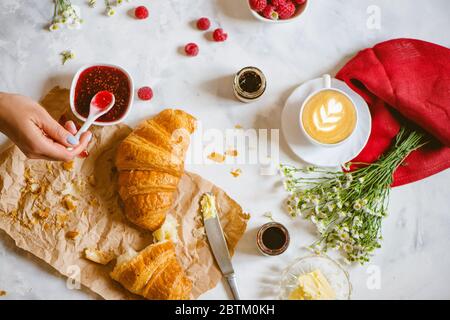 Frische Croissants, Kaffee, Marmelade, Butter und Himbeere auf dem Tisch. Flaches Lay. Stockfoto