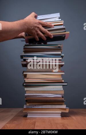 Hände einer Person, die einen Stapel Bücher bestellt, die die Informationen darstellen Stockfoto