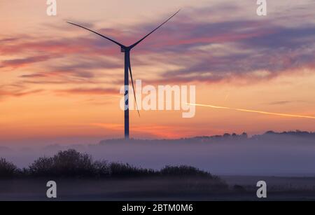 Dummerstorf, Deutschland. Mai 2020. Nebel liegt über der Landschaft, während eine Windturbine als dunkle Silhouette in der Morgendämmerung steht. Quelle: Jens Büttner/dpa-Zentralbild/dpa/Alamy Live News Stockfoto