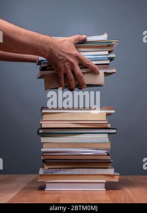 Hände einer Person, die einen Stapel Bücher bestellt, die die Informationen darstellen Stockfoto