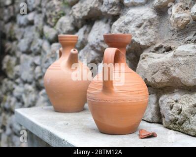 Alte Tonkrüge auf einem Steinwand Hintergrund Stockfoto