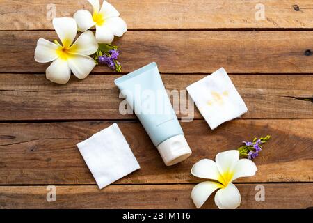 Feuchtigkeitsspendende Reinigungscreme mit Baumwolle für sauberes Make-up Gesundheit Pflege für die Haut Gesicht und weiße Blumen frangipani Lifestyle-Stil Frau auf Holz Stockfoto