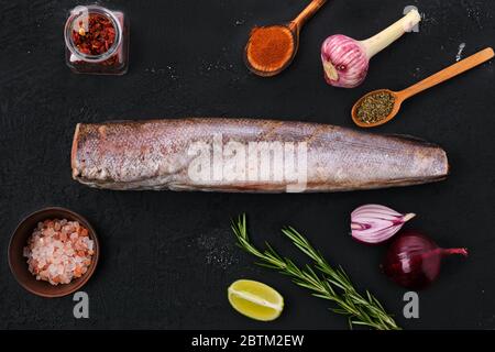 Seehecht mit Gewürz auf schwarzem Hintergrund Stockfoto