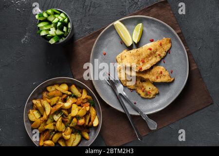 Gebratenes Seehechtfilet mit Gewürzen und gerösteten Kartoffelspalten Stockfoto