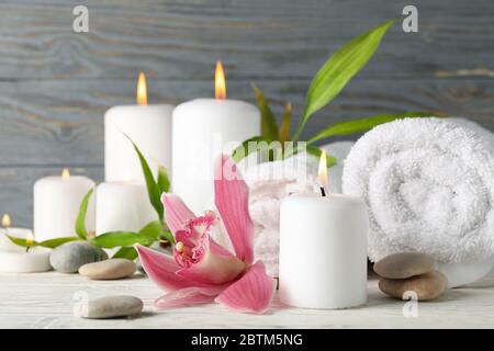 Komposition mit Kerzen, Handtüchern, Steinen und Orchidee auf Holztisch. Zen-Konzept Stockfoto