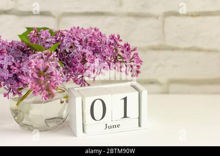 1. Juni auf einem Holzkalender neben Blumen. Der erste Tag des Sommers. Kindertag. Platz zum Kopieren. Stockfoto