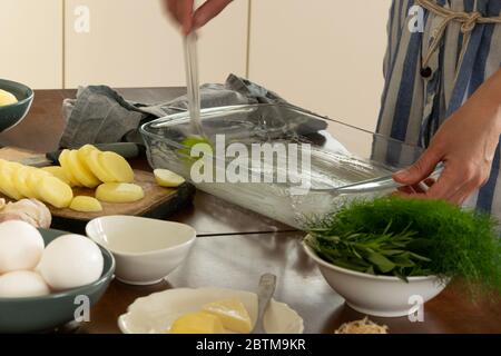 Frau Hände breitet sich mit geschmolzener Butter zu hausgemachten Kartoffelgartin machen Stockfoto