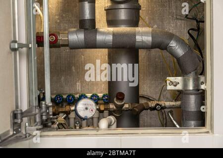 Schalten Sie heißes Wasser. Sanitär-Schrank. Wasserzähler, Kollektor, Wasserdrucksensor Stockfoto