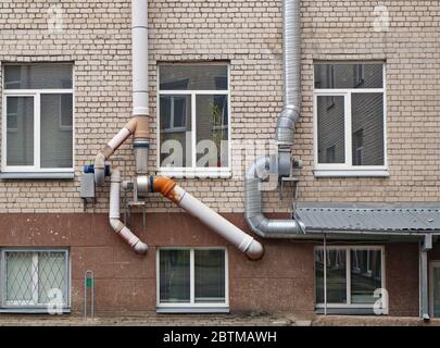 Dicke, leistungsstarke Lüftungsrohre Klimaanlagen auf den alten weißen Ziegelsteinen Schulwand montiert Stockfoto