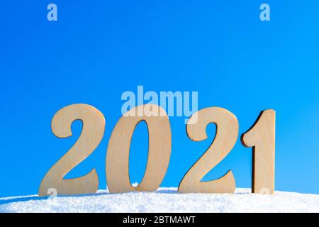 Wir Feiern Das Neue Jahr 2021. Holzfiguren 2021 auf einer natürlichen winterverschneiten Oberfläche.beleuchtet von der hellen Sonne gegen einen klaren blauen Himmel. Natürlicher Style Stockfoto