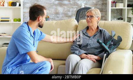 Krankenschwester im Gespräch mit einer alten Frau, die an parkinson im Pflegeheim leidet Stockfoto