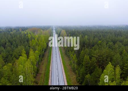 Straße mit Autos im Wald zwischen grünen Bäumen, die Aussicht von oben Stockfoto