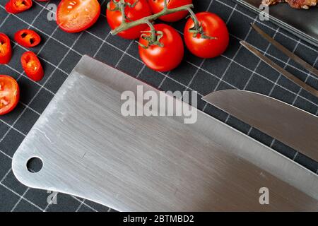 Nahaufnahme von Kirschtomaten und Küchenmesser auf karierter Tischdecke Stockfoto