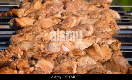 Frisches Fleisch, das auf Spieße gekleidet ist, wird auf einem Bräter oder Grill gebraten. Der Küchenchef bereitet Fleisch in einem Café oder Restaurant zu. Frisches rohes und gebratenes Schweinefleisch, Rind und Lamm Stockfoto