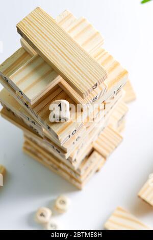 Hoher Turm aus Holzblöcken mit Nummer eins auf der Spitze gebaut. Spiel Jenga für Kinder spielen auf einem hellgrauen Hintergrund mit Kopierraum. Konzept von Stockfoto