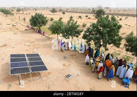 NIGER, Maradi, Dorf Dan Bako, Projekt Armutsbekämpfung und Anpassung des Klimawandels, Gemüseanbau mit Bewässerung, Wasser wird mit Solarpumpe gepumpt, Frauen am Solarpanel / Projekt Armutsbekaempfung und Anpassung an den Klimawandel, Gemüsegarten mit Bewässerung, Solar Panel für Wasserpumpe zur Bewässerung Stockfoto