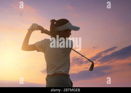 Junge Frauen Asien Spieler Golfschwung auf Kurs mit Sonnenuntergang Himmel Dämmerung Hintergrund geschossen. Übung und Gesundheit Konzept. Golf üben, um ein Profi zu sein Stockfoto