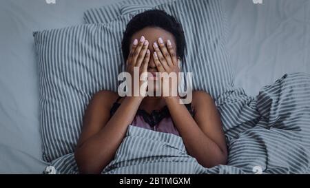 afroamerikanisches Mädchen schloss die Augen mit den Händen im Bett Stockfoto