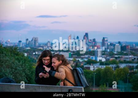 London, Großbritannien - 5. Oktober 2019 - zwei weibliche Touristen genießen das Selfie, das mit Blick auf die Skyline von London vom Parliament Hill in Hampstead Heath aufgenommen wurde Stockfoto