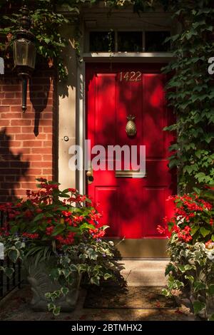 Vertikale Aufnahme des roten Eingangstors zu einer von der Sonne beleuchteten Luxuswohnung, nahe North Side, Chicago, Illinois, USA Stockfoto
