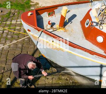 Newhaven, Edinburgh, Schottland, Großbritannien, 27. Mai 2020. UK Wetter: Ein Rumpf eines Fischerboots wird mit einem Power Jet Spray gereinigt Stockfoto