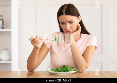 Unglückliche Frau Müde Von Diät Essen Grünen Salat Zu Hause Stockfoto