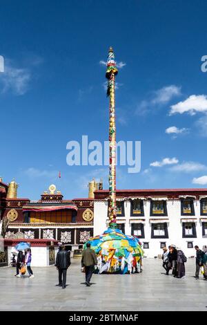 Einer der großen Gebetsmasten, die am Eingang zum Jokhang-Tempel hoch stehen, geschmückt mit Gebetsfahnen vor dem schönen klaren, blauen Himmel Stockfoto