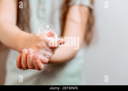 Kinderhände in Seifenschaum. Coronavirus-Pandemie. Stockfoto