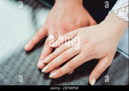 Junge Paar Hände. Hochzeitstag. Im Freien. Glastisch Stockfoto
