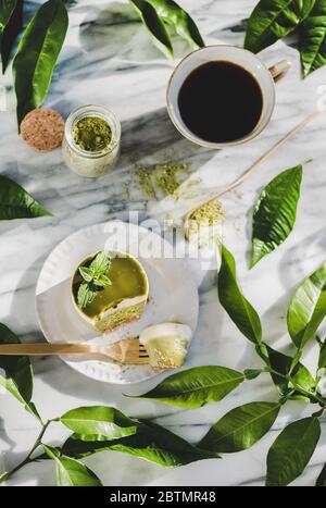 Flacher Lay aus grünem Matcha-Käsekuchen und schwarzem Kaffee in der Tasse Stockfoto