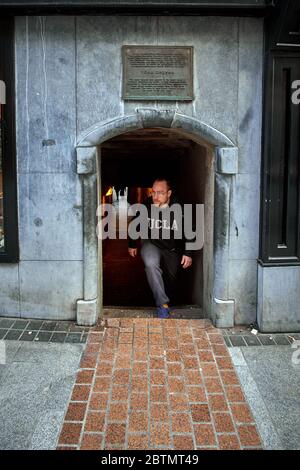 Wexford, Irland - 10/30/2018: Mann im UCLA-Hemd verlässt den kurzen Torbogen der Keyser’s Lane aus dem 16. Jahrhundert an der South Main St. in Wexford Irland. Stockfoto