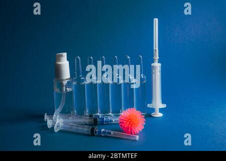 Abstraktes Modell des Coronavirus, Ampulle mit Medizin und Flasche mit antibakteriellem Gel für Hände auf blauem Hintergrund gegen Coronavirus. Stockfoto