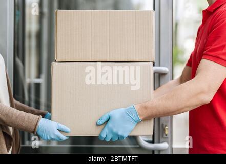 Online-Shopping und Lieferung an Tür Konzept. Kurier liefert Paket zu Haus während der Pandemie Stockfoto