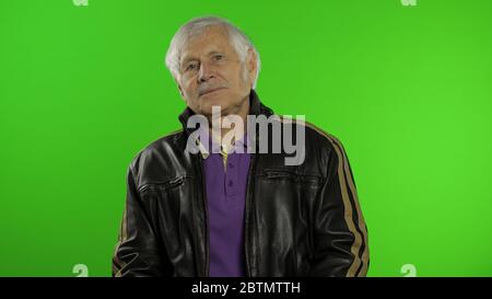 Ältere stilvolle Großvater kaukasischen Rocker und Biker reifen Mann auf Chroma-Schlüssel Hintergrund. Alte ältere Großeltern in Mode Lederjacke. Grüner Bildschirm Stockfoto