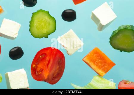 Zutaten für den Salat. Caesar Salat Rezept. Frisches Gemüse (Tomaten, Gurken, Oliven) und Käse auf blauem, minimalem Hintergrund. Stockfoto