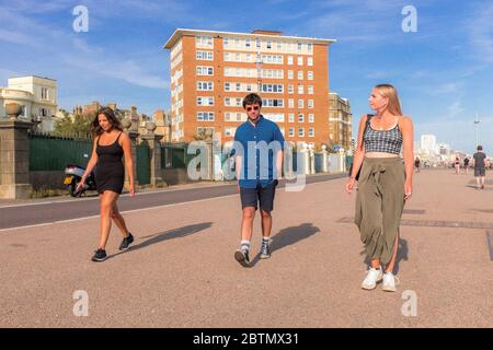 Drei junge Menschen gehen am Brighton Beach entlang, während sie am 26. Mai 2020 soziale Distanz genießen Stockfoto