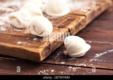 Rohe hausgemachte Pelmeni (Knödel) mit Fleisch auf Holzhintergrund. Stockfoto