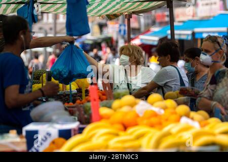 Menschen, die Gesichtsmasken an einem Obst- und Gemüsemarkt in Walthamstow, East London, tragen, nachdem Maßnahmen eingeführt wurden, um das Land aus der Blockierung zu bringen. Stockfoto