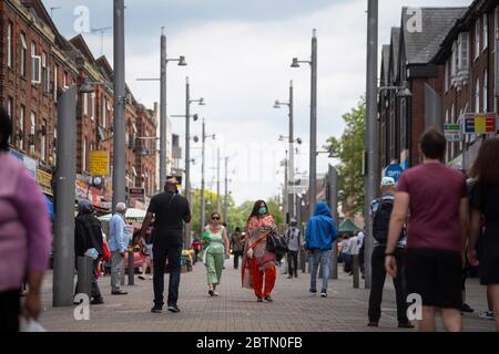 Eine Frau mit Gesichtsmaske geht nach der Einführung von Maßnahmen, um das Land aus der Blockaden zu bringen, in Walthamstow, East London, entlang einer Hauptstraße. Stockfoto