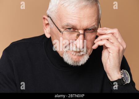 Alt attraktiver Mann mit grauen Haaren und Bart in Brillen und Pullover traumhaft in der Kamera über beigem Hintergrund isoliert Stockfoto